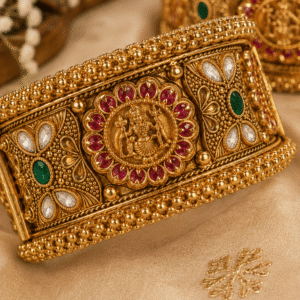 Close-up of antique temple bangle with deity medallion, ruby red, green and white stones